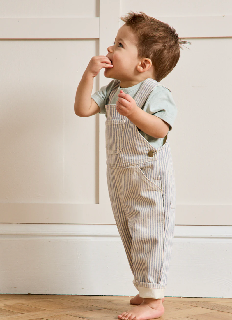 Toddler in overalls climbing and playing